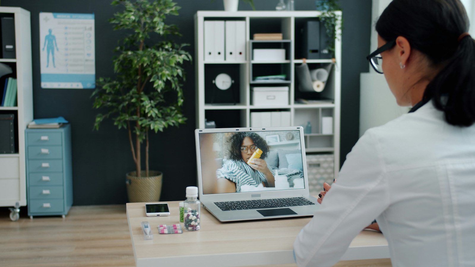 Physician consulting with a patient over a telehealth video call on a laptop